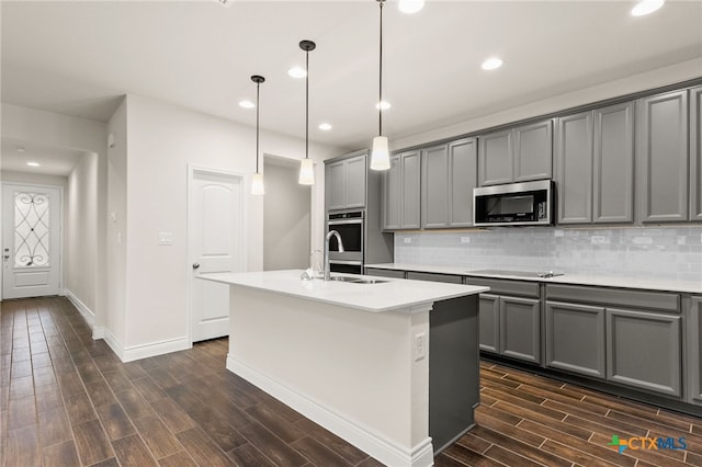 kitchen featuring a center island with sink, gray cabinets, and stainless steel appliances