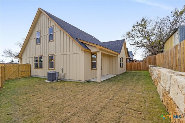 back of property with central air condition unit and a lawn