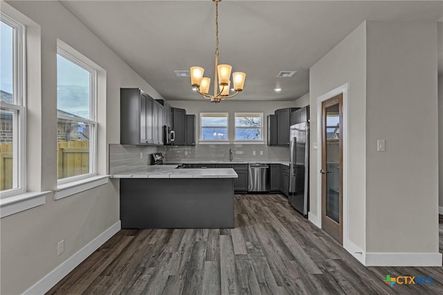 kitchen featuring sink, kitchen peninsula, backsplash, stainless steel appliances, and light stone counters