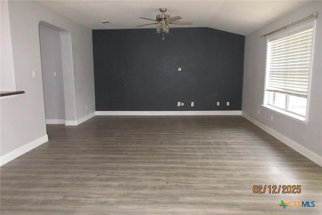 spare room with dark wood-type flooring, vaulted ceiling, baseboards, and ceiling fan