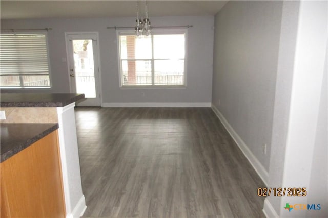 unfurnished dining area with dark wood-style floors and baseboards