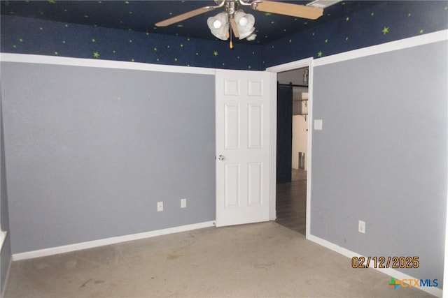 unfurnished bedroom featuring a barn door, baseboards, and carpet flooring