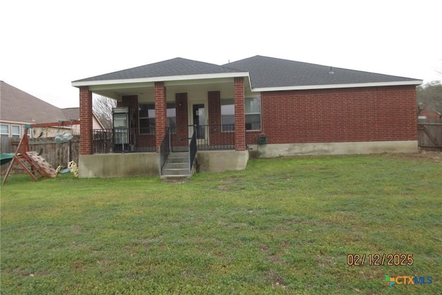 back of house with fence, a porch, a lawn, and brick siding