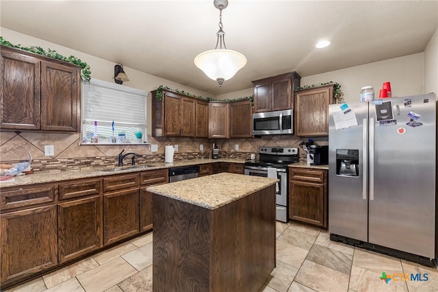 kitchen with light stone counters, a center island, sink, pendant lighting, and appliances with stainless steel finishes