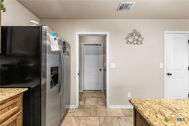 kitchen with stainless steel refrigerator with ice dispenser and light stone countertops