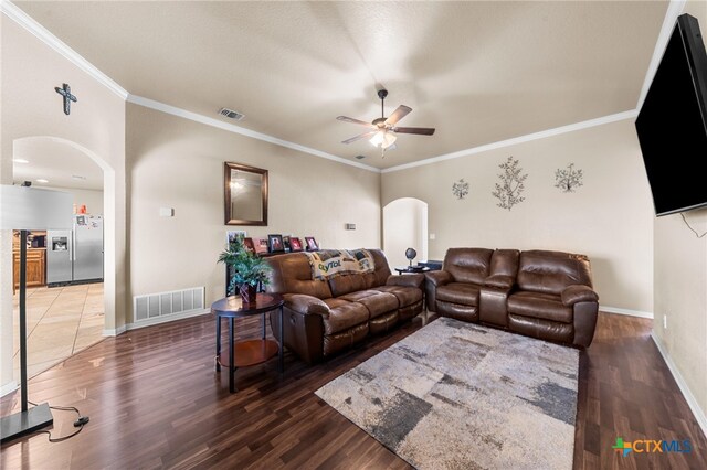 living room with dark hardwood / wood-style flooring, ceiling fan, and crown molding