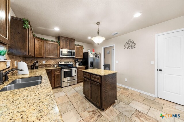 kitchen with stainless steel appliances, a center island, decorative backsplash, sink, and decorative light fixtures