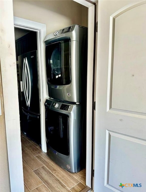 washroom with hardwood / wood-style floors and stacked washing maching and dryer