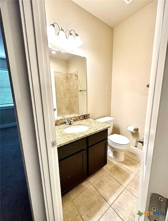 bathroom with vanity, walk in shower, tile patterned flooring, and toilet