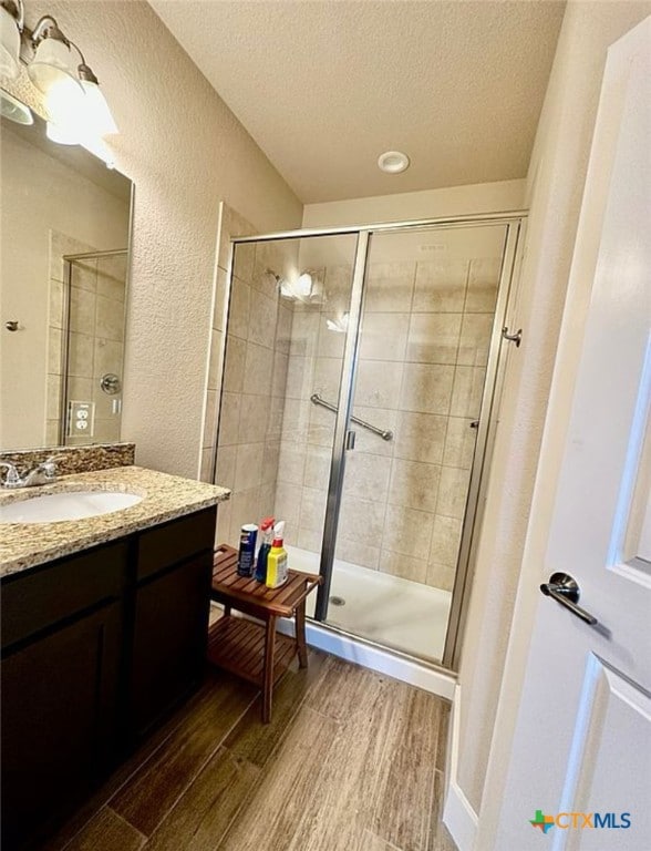 bathroom with vanity, walk in shower, wood-type flooring, and a textured ceiling