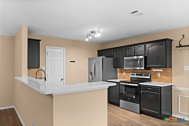 5300 Two Step Pl, Killeen, TX 76542 - kitchen with stainless steel appliances, light wood-style floors, tasteful backsplash, and a peninsula