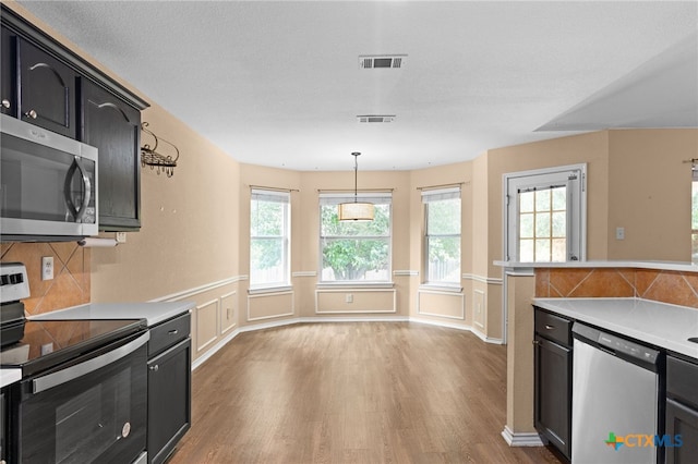 5300 Two Step Pl, Killeen, TX 76542 - kitchen featuring appliances with stainless steel finishes, wood finished floors, light countertops, dark cabinets, and wainscoting