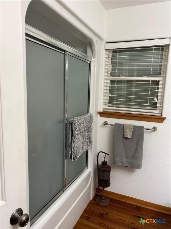 bathroom with enclosed tub / shower combo and wood-type flooring