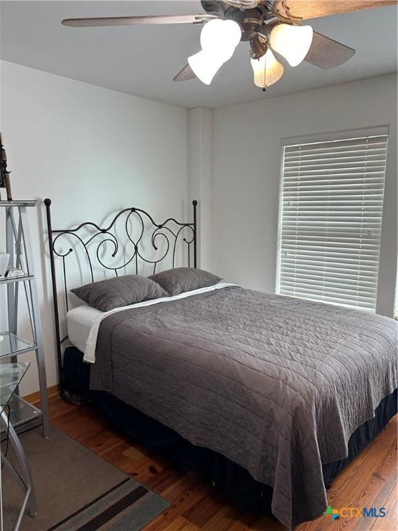 bedroom with dark hardwood / wood-style flooring and ceiling fan