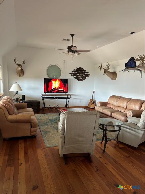 living room with hardwood / wood-style flooring, ceiling fan, and vaulted ceiling