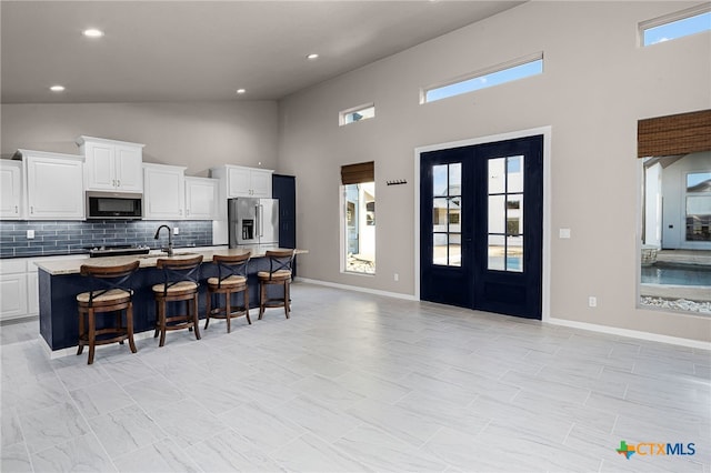 111 Western Oaks, New Braunfels, TX 78132 - kitchen with white cabinetry, tasteful backsplash, stainless steel appliances, high vaulted ceiling, and a breakfast bar