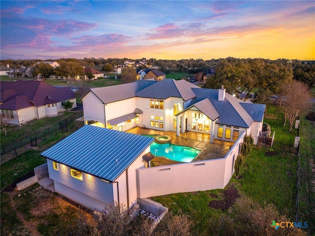111 Western Oaks, New Braunfels, TX 78132 - back of house with a pool with connected hot tub, a standing seam roof, a chimney, a fenced backyard, and metal roof