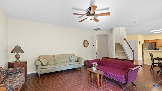 living area with a ceiling fan, arched walkways, stairs, baseboards, and wood finished floors