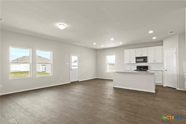 1211 N Teychas Dr, Kyle, TX 78640 - kitchen with white cabinets, black microwave, stove, recessed lighting, and dark wood-type flooring
