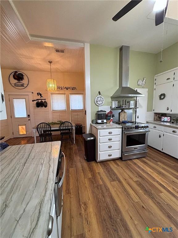 kitchen with white cabinetry, stainless steel stove, wall chimney range hood, and dark wood-style flooring