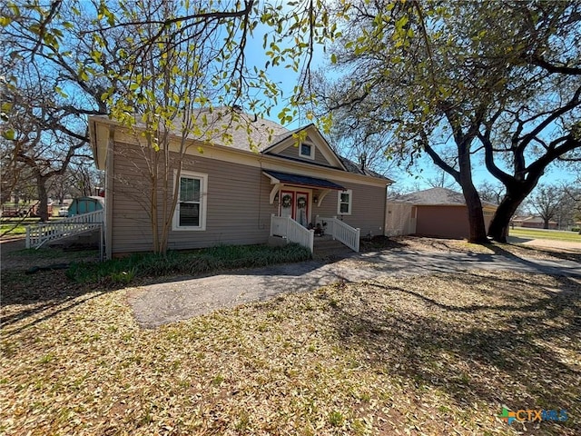 view of front of property with an outbuilding, driveway, and fence