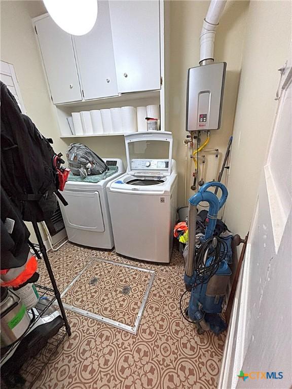 laundry area with tile patterned flooring, cabinet space, tankless water heater, and washer and clothes dryer