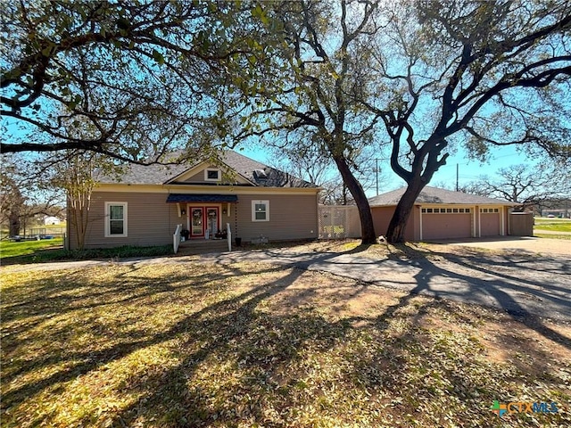 view of front of home featuring a garage, a front yard, an outdoor structure, and driveway