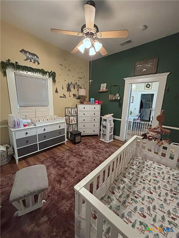 bedroom with visible vents, a ceiling fan, lofted ceiling, and wood finished floors