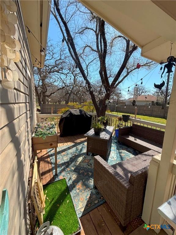 wooden deck with area for grilling and a fenced backyard