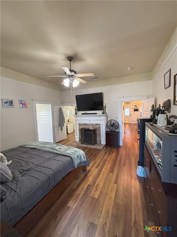 bedroom with a fireplace, wood finished floors, and ceiling fan