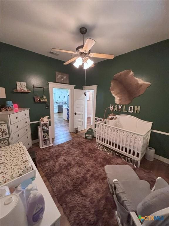 bedroom with ceiling fan, baseboards, carpet, and a nursery area