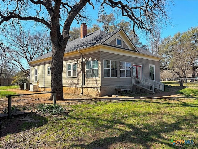 view of front of home featuring a front yard, central AC unit, fence, and a chimney