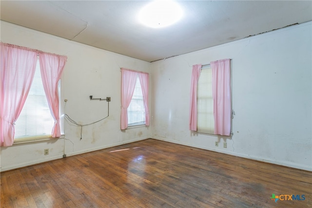 empty room with dark hardwood / wood-style floors and plenty of natural light