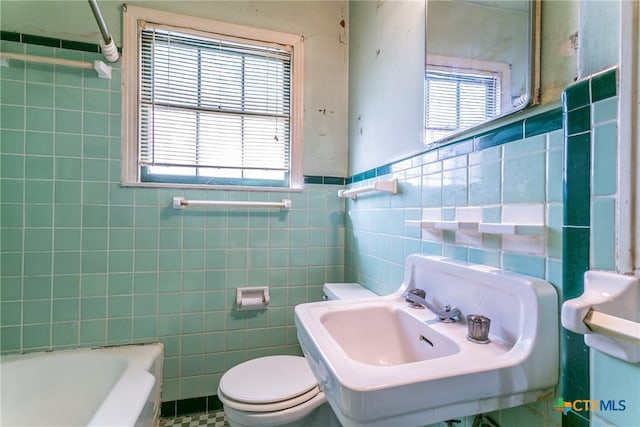 bathroom with toilet, tile walls, sink, and plenty of natural light