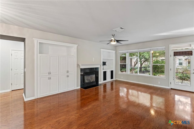 unfurnished living room with a tiled fireplace, ceiling fan, and wood-type flooring