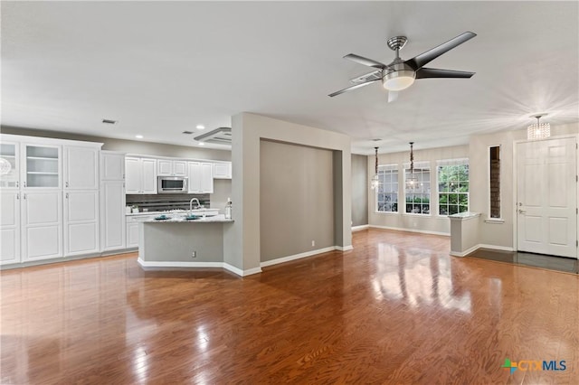 unfurnished living room with ceiling fan, hardwood / wood-style floors, and sink