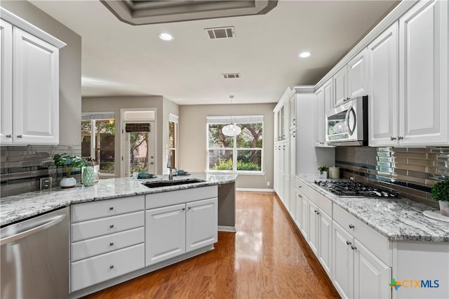 kitchen featuring a wealth of natural light, sink, stainless steel appliances, decorative backsplash, and white cabinets