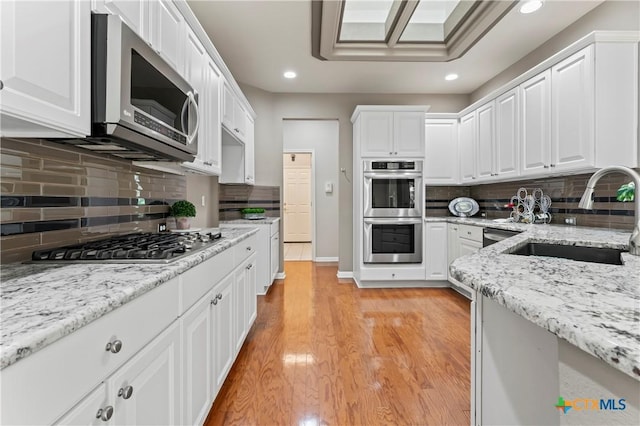 kitchen with decorative backsplash, sink, white cabinets, and appliances with stainless steel finishes