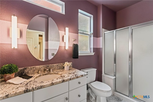 bathroom featuring vanity, a shower with shower door, and toilet