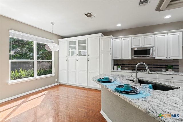 kitchen with decorative backsplash, sink, white cabinets, and light stone countertops