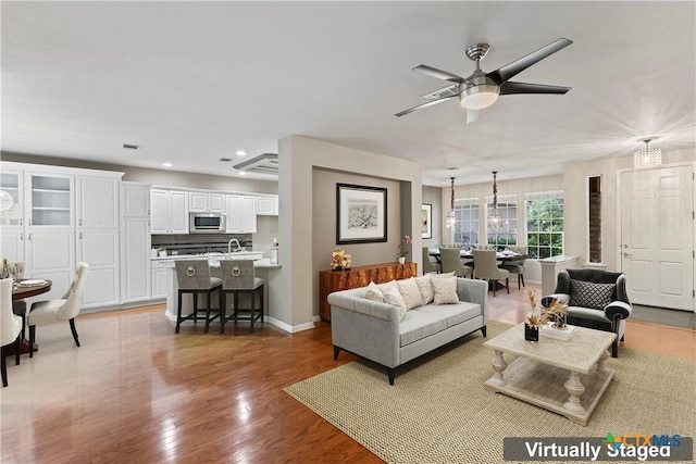 living room with ceiling fan, sink, and light hardwood / wood-style flooring