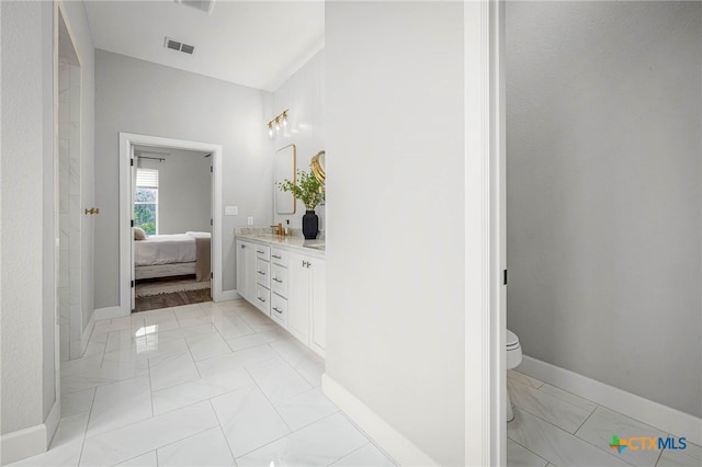 ensuite bathroom featuring baseboards, visible vents, toilet, ensuite bathroom, and vanity