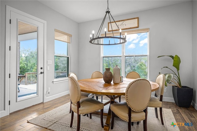 dining area featuring an inviting chandelier, wood finished floors, and baseboards