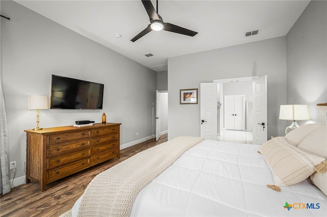 bedroom featuring a ceiling fan, visible vents, baseboards, and wood finished floors