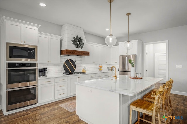 kitchen featuring white cabinets, dark wood-style floors, a sink, stainless steel appliances, and backsplash