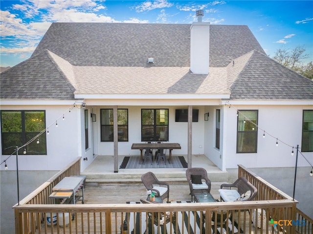 back of house with outdoor dining space, a chimney, an outdoor living space, and roof with shingles