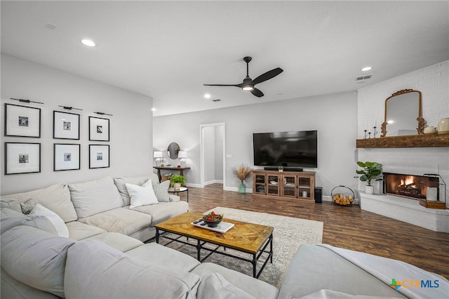 living area with baseboards, visible vents, wood finished floors, a brick fireplace, and recessed lighting