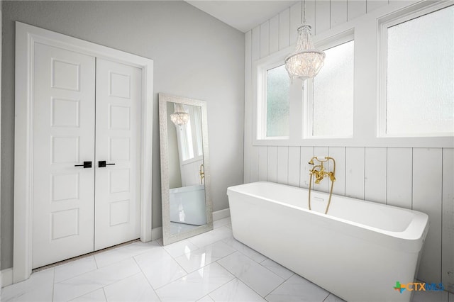 bathroom featuring a soaking tub and marble finish floor