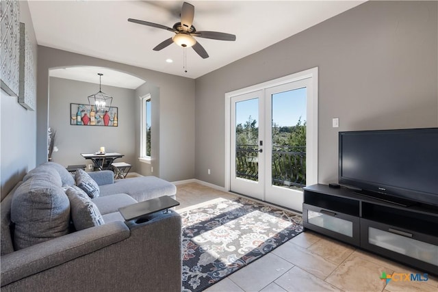 living room with arched walkways, ceiling fan with notable chandelier, baseboards, marble finish floor, and french doors