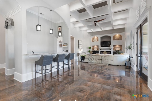 interior space with baseboards, coffered ceiling, a ceiling fan, marble finish floor, and a high ceiling